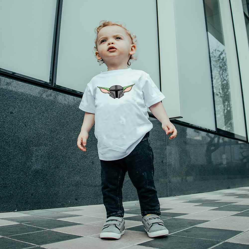 An image of a child wearing a white t-shirt with a design of Baby Mandalorian on the front.
