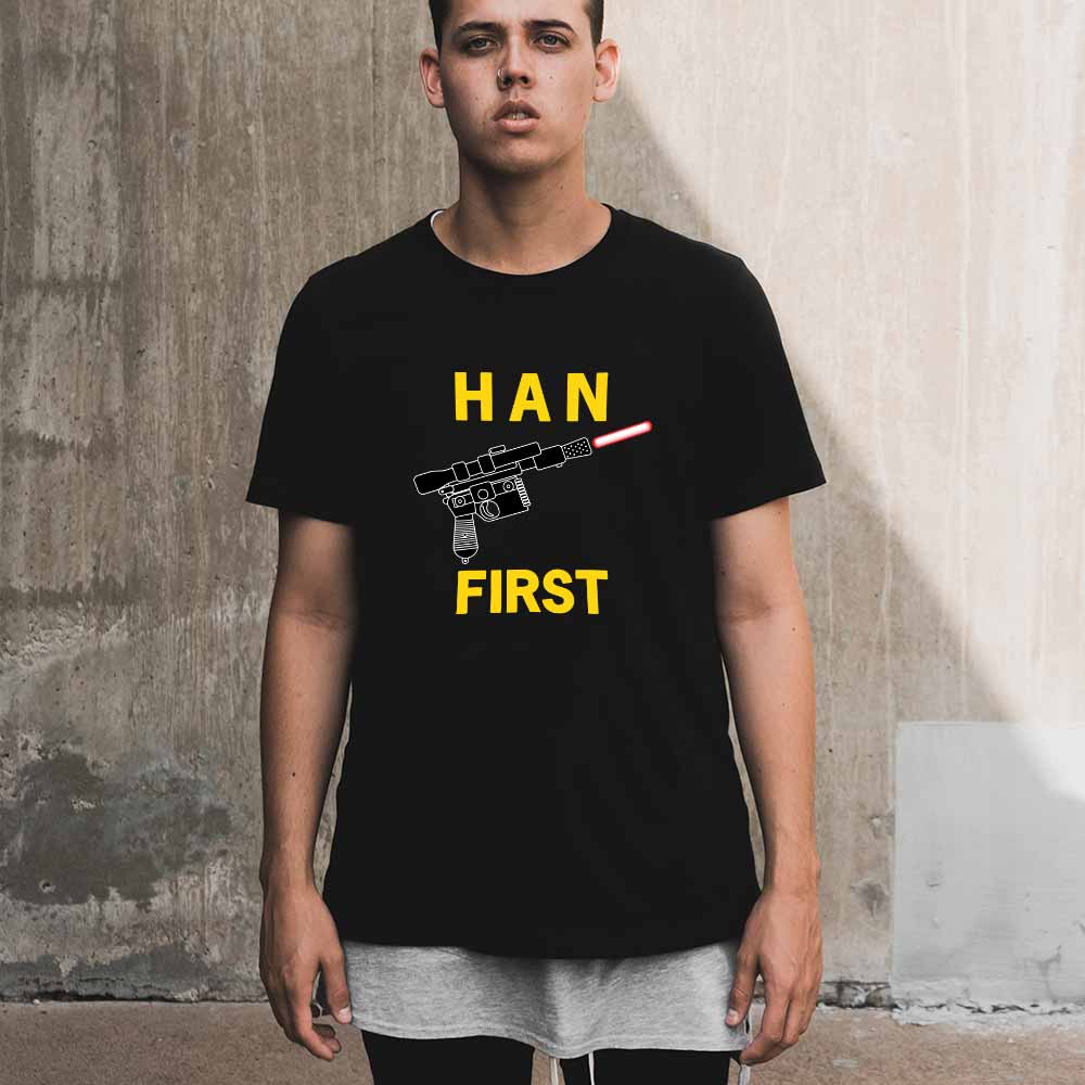 An image of a man wearing a black t-shirt with a design of Han's blaster surrounded by the text 'Han' and 'Shot' on the front.
