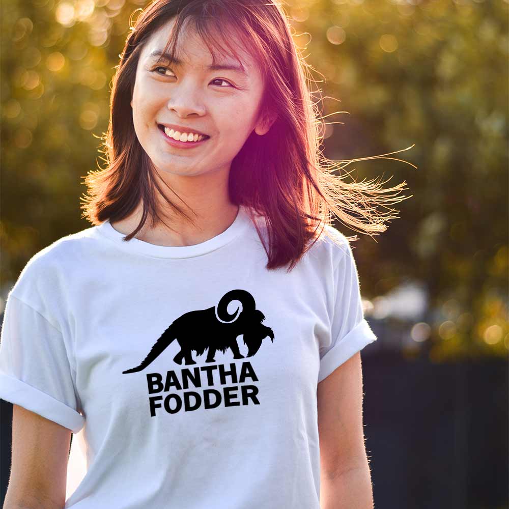 An image of a woman wearing a white t-shirt with a design of a bantha with the text 'Bantha Fodder' on the front.

